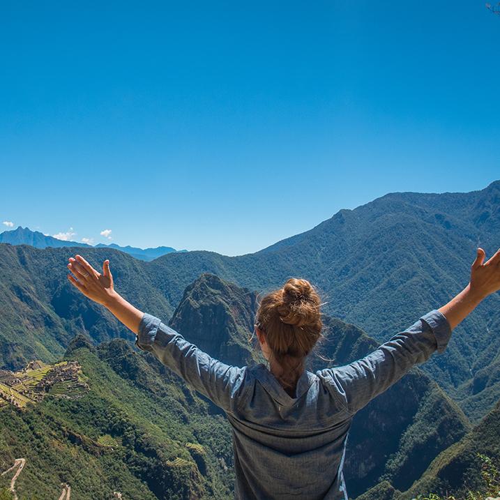 woman on a mountaintop with arms outstretched victoriously