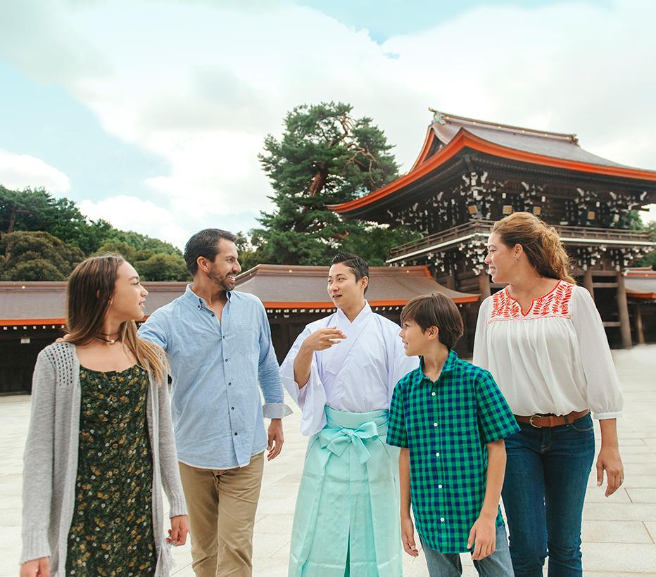 a family of four are guided from a Japanese temple by their tour guide