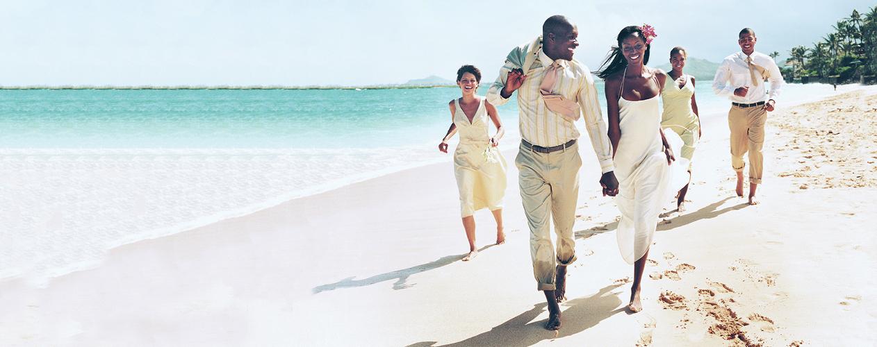 Destination wedding party running along beach