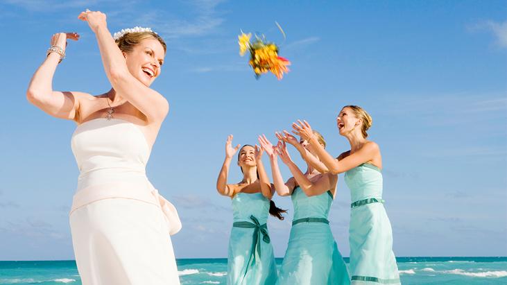 Bride bouquet toss to her bridal party at a beach destination wedding